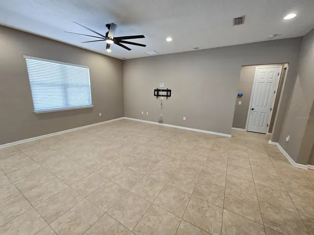 an empty room with windows and fan