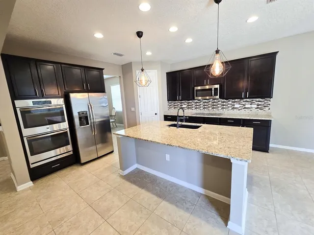a kitchen with stainless steel appliances kitchen island granite countertop a stove and a refrigerator