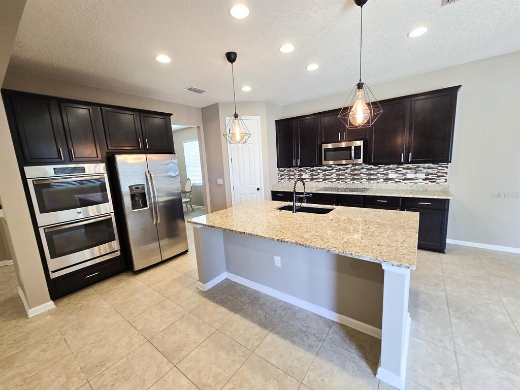 3543 Meadow Breeze Loop Ocoee, FL 34761 - Photo 8 of 38 a kitchen with stainless steel appliances kitchen island granite countertop a stove and a refrigerator