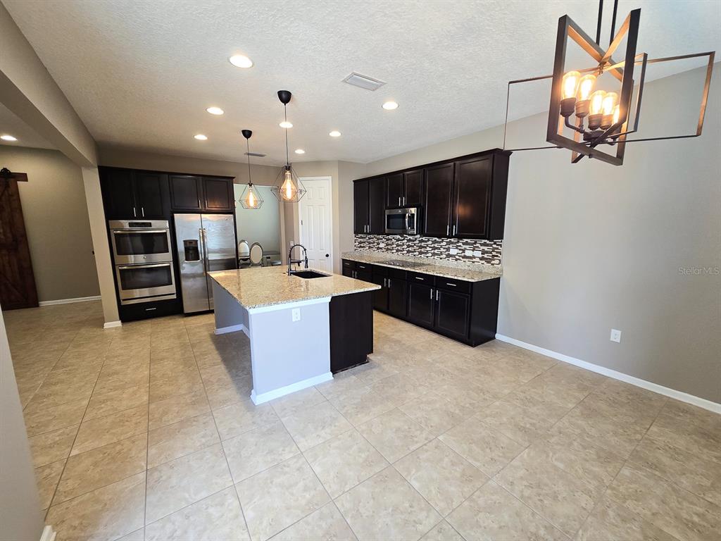 3543 Meadow Breeze Loop Ocoee, FL 34761 - Photo 10 of 38 a large room with kitchen island a sink a stove and a refrigerator