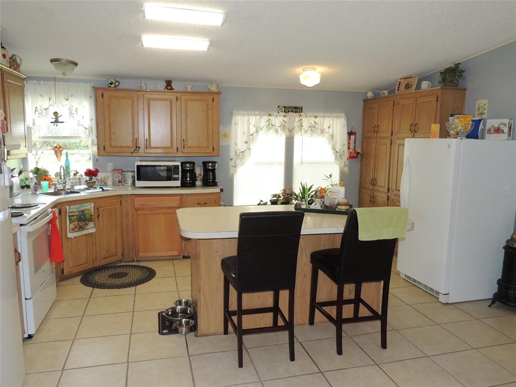 7050 Southeast Co Road 337 Morriston, FL 32668 - Photo 43 of 67 a kitchen with a dining table chairs and refrigerator