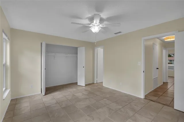 a view of an empty room with chandelier fan
