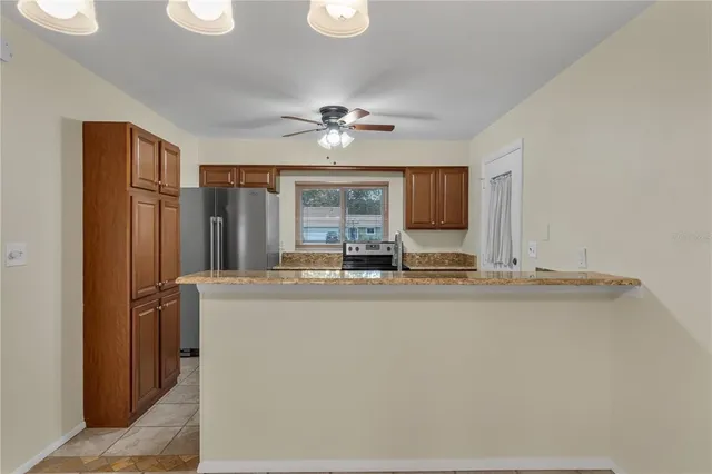 a view of open kitchen with granite countertop cabinets and refrigerator