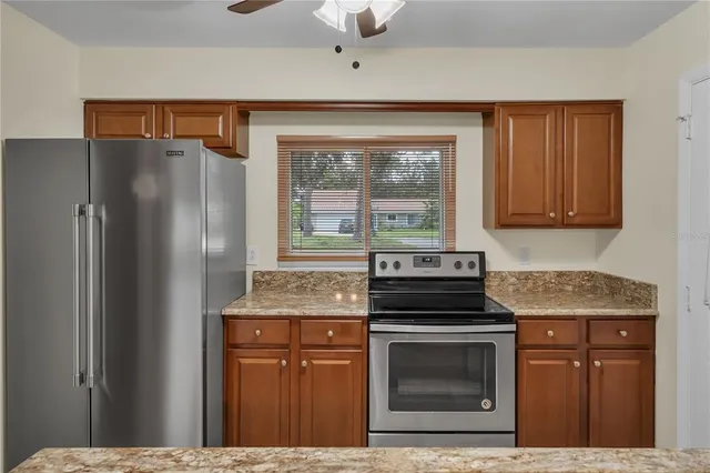 a kitchen with granite countertop a refrigerator stove and sink