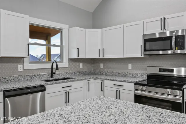 a open kitchen with white cabinets and stainless steel appliances