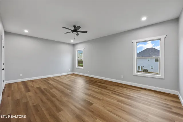 an empty room with wooden floor and ceiling fan
