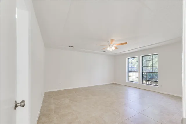 an empty room with windows and chandelier fan