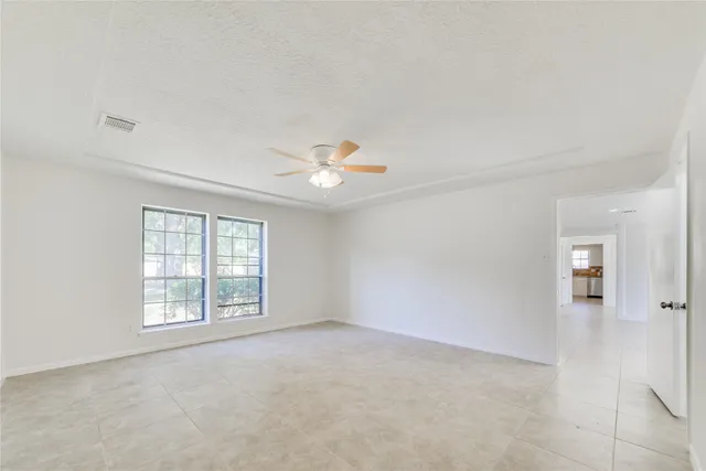 an empty room with windows and ceiling fan view