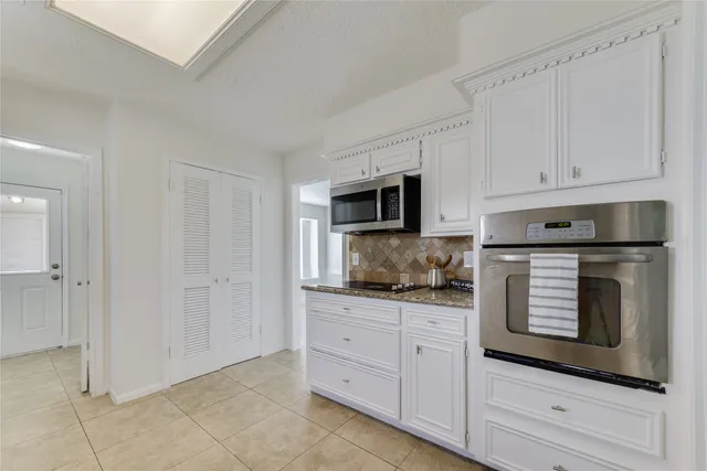 a kitchen with white cabinets and appliances