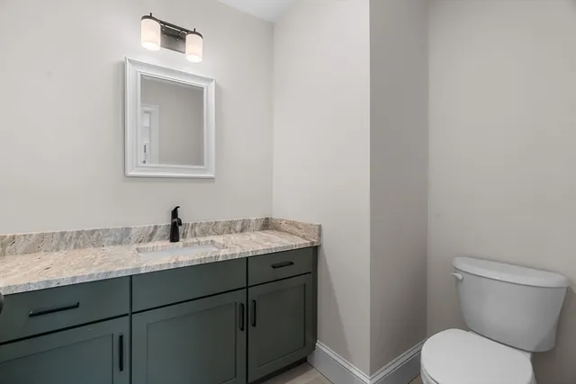 a bathroom with a granite countertop toilet sink and mirror