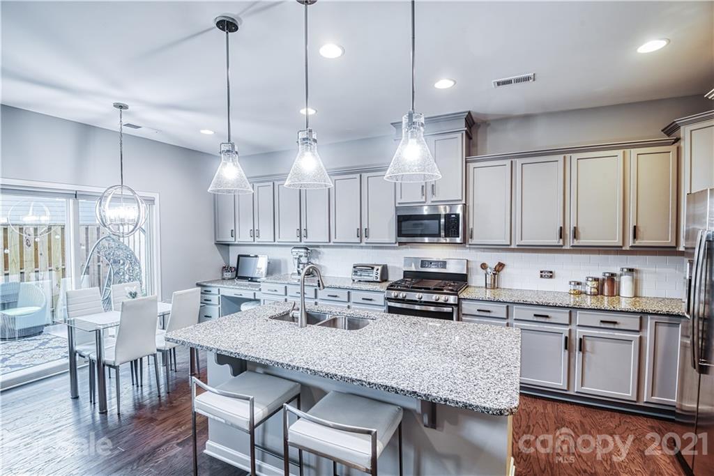 606 Amber Meadows Way Tega Cay, SC 29708 - Photo 2 of 23 a kitchen with stainless steel appliances granite countertop a stove a refrigerator a sink a stove and white cabinets with wooden floor