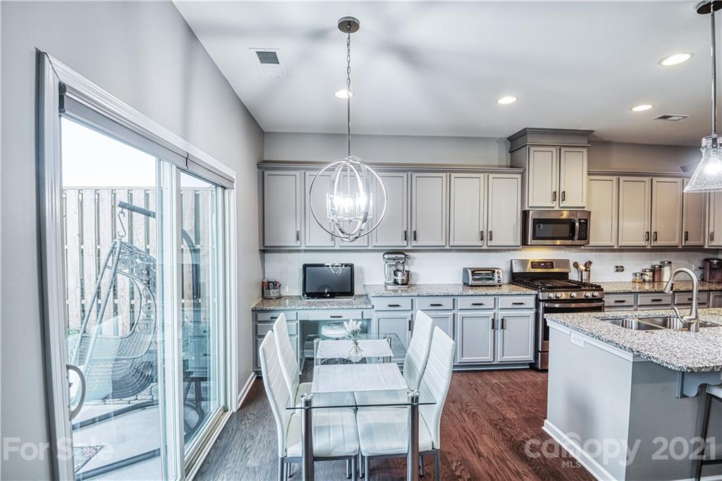 606 Amber Meadows Way Tega Cay, SC 29708 - Photo 4 of 23 a kitchen with stainless steel appliances granite countertop a stove top oven a sink dishwasher a dining table and chairs with wooden floor