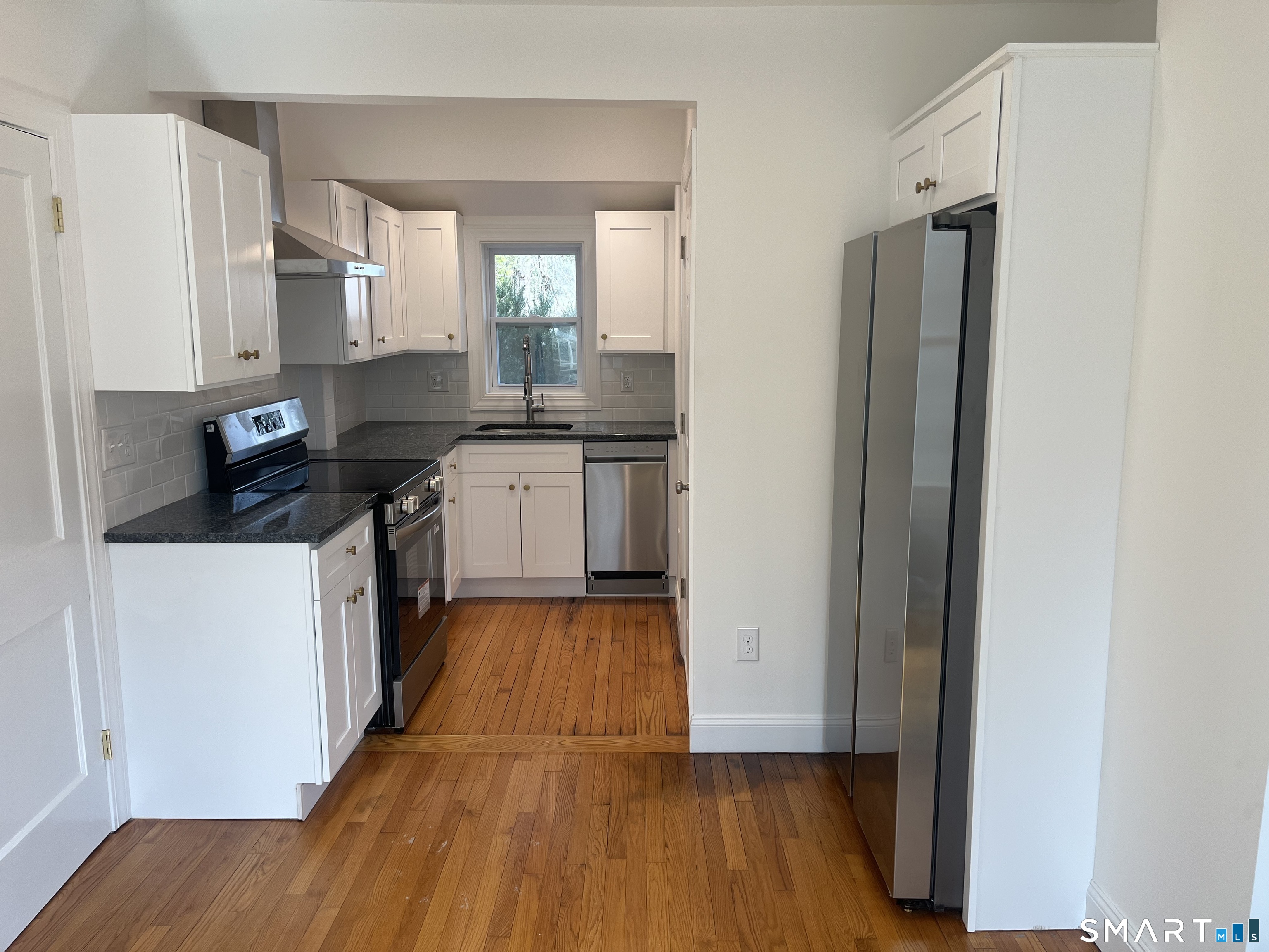 a kitchen with kitchen island wooden floors appliances and cabinets