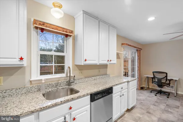 a kitchen with granite countertop a sink stove and cabinets