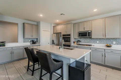 a large kitchen with a counter top space a sink appliances and cabinets