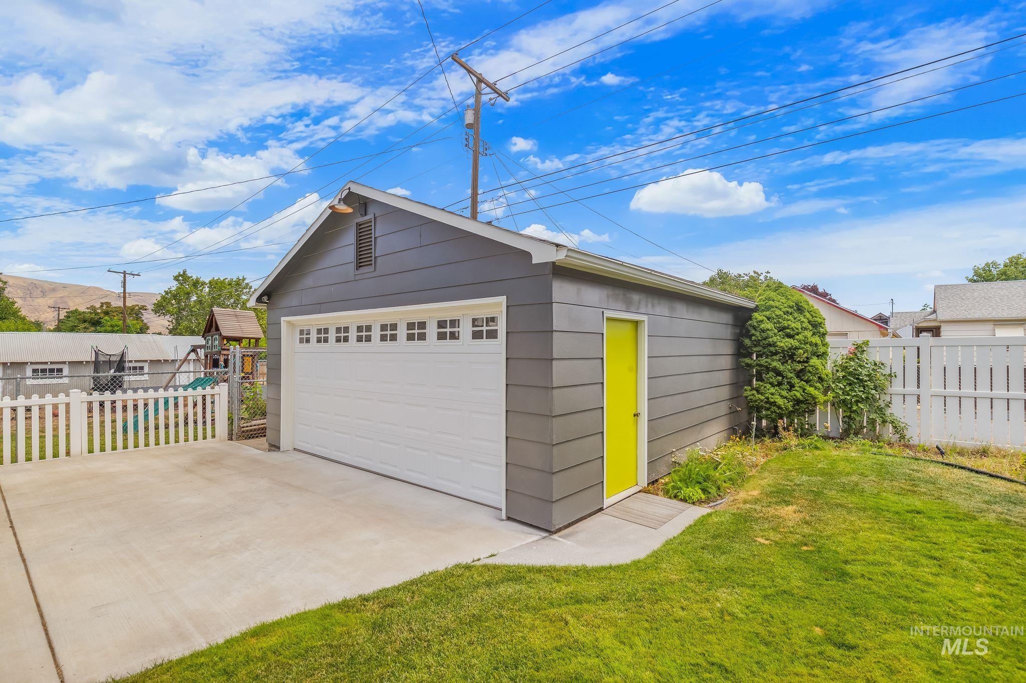 1315 8th Street Clarkston, WA 99403 - Photo 31 of 37 Detached garage with horizontal siding, a white sectional overhead door with upper windows, and an auxiliary side entry with a vibrant yellow door