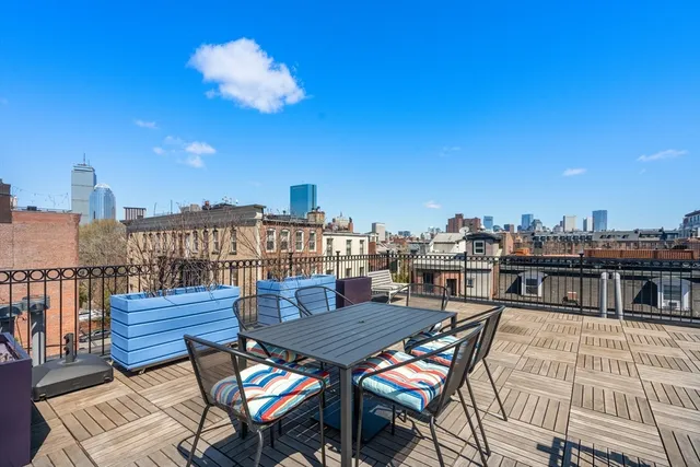 a view of a rooftop deck with chairs and wooden floor