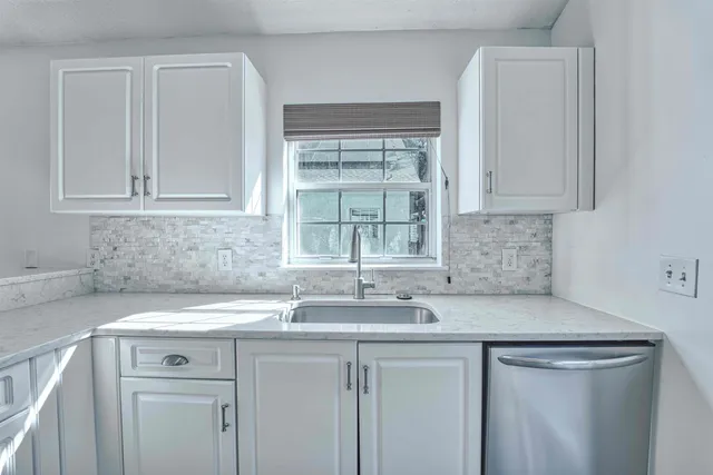 a view with granite countertop a sink white cabinets and a granite counter tops