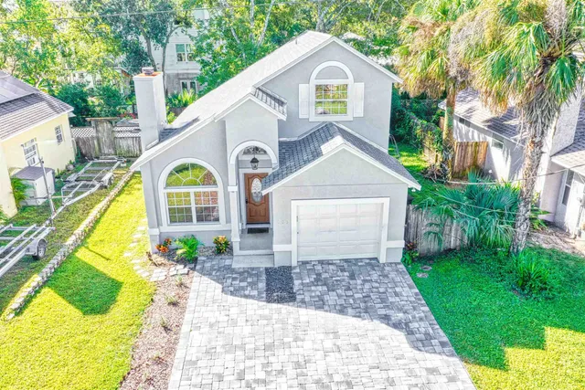 a view of a white house with a yard and large tree