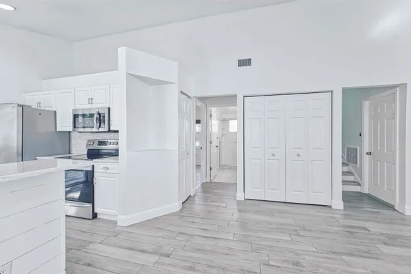 a view of a kitchen with refrigerator and wooden floor