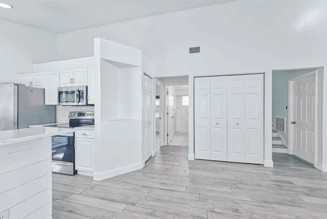 a view of a kitchen with refrigerator and wooden floor