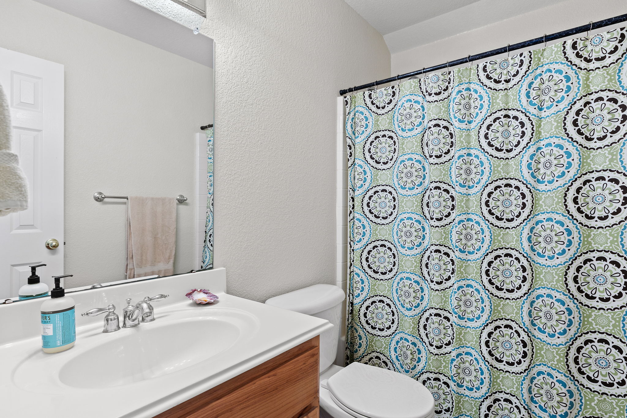 202 The Oaks Boulevard Elgin, TX 78621 - Photo 30 of 40 Full bath with vanity, a textured wall, and a shower with shower curtain