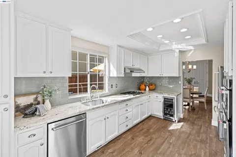 a kitchen with a sink white cabinets and wooden floor