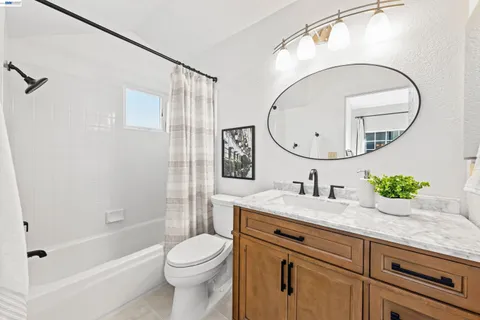 a bathroom with a granite countertop sink mirror vanity and toilet