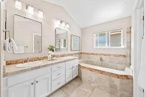 a spacious bathroom with a tub sink and mirror