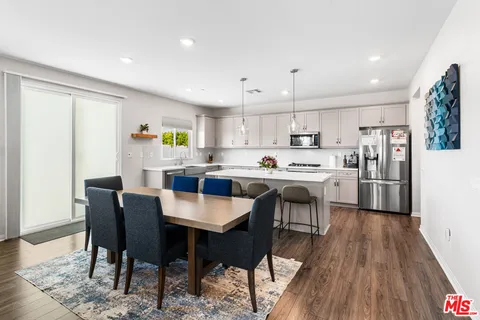 a kitchen with kitchen island a stove a table a sink a refrigerator and cabinets