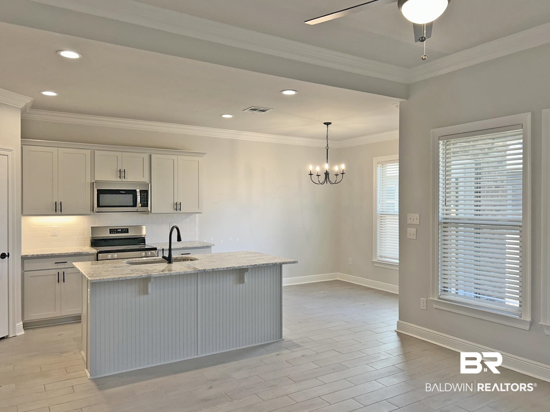 1748 Breckinridge Place Foley, AL 36535 - Photo 9 of 25 Kitchen with stainless steel appliances, light stone counters, decorative backsplash, an island with sink, and ornamental molding