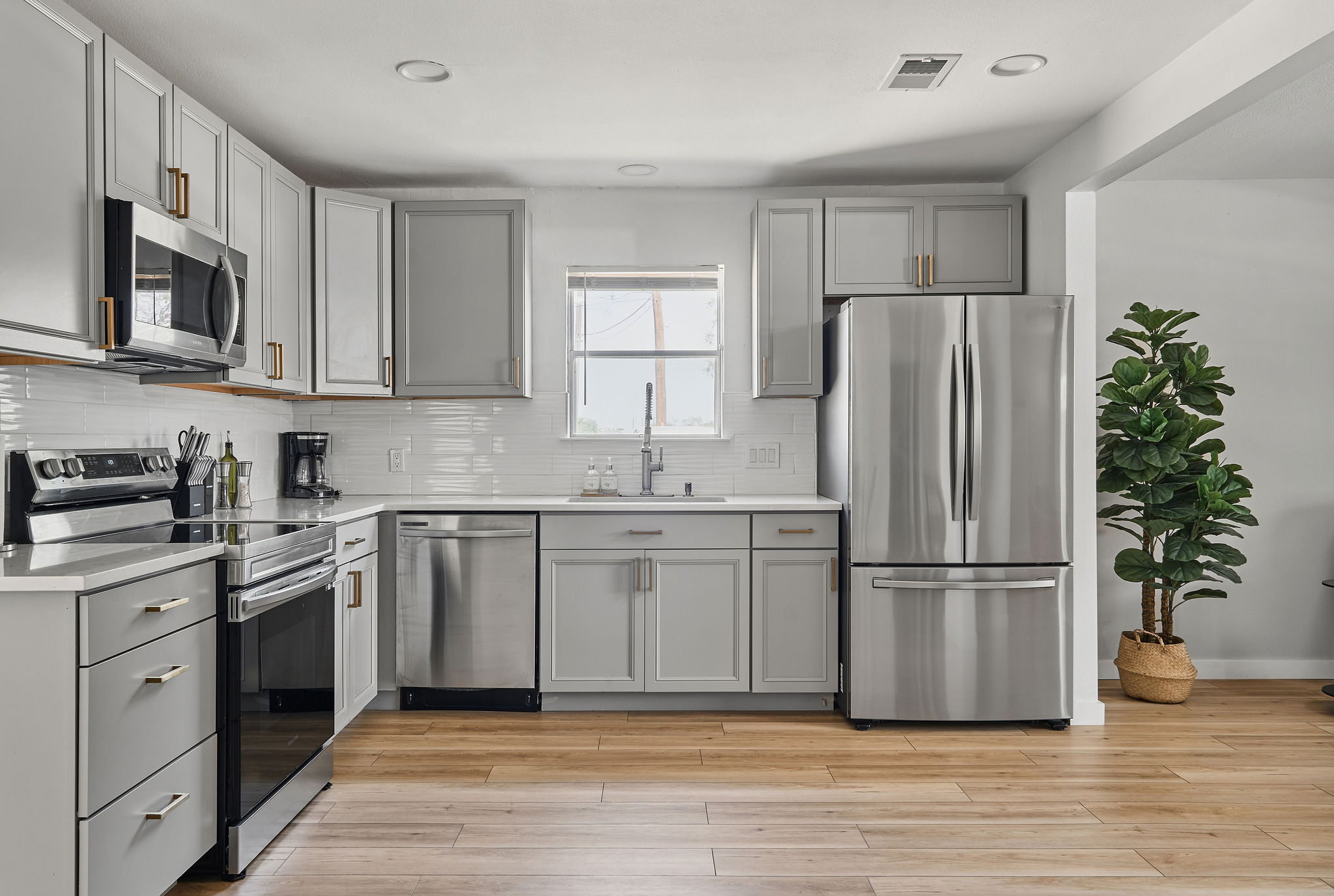 7706 Delafield Lane Austin, TX 78752 - Photo 19 of 28 Kitchen with gray cabinets, stainless steel appliances, light wood finished floors, decorative backsplash, and recessed lighting