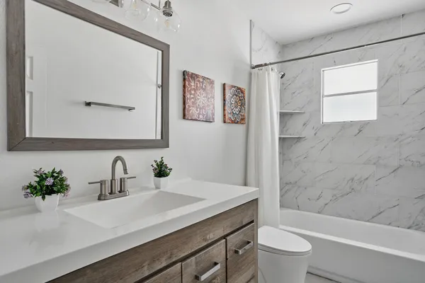 a bathroom with a sink a toilet a mirror a vanity and shower