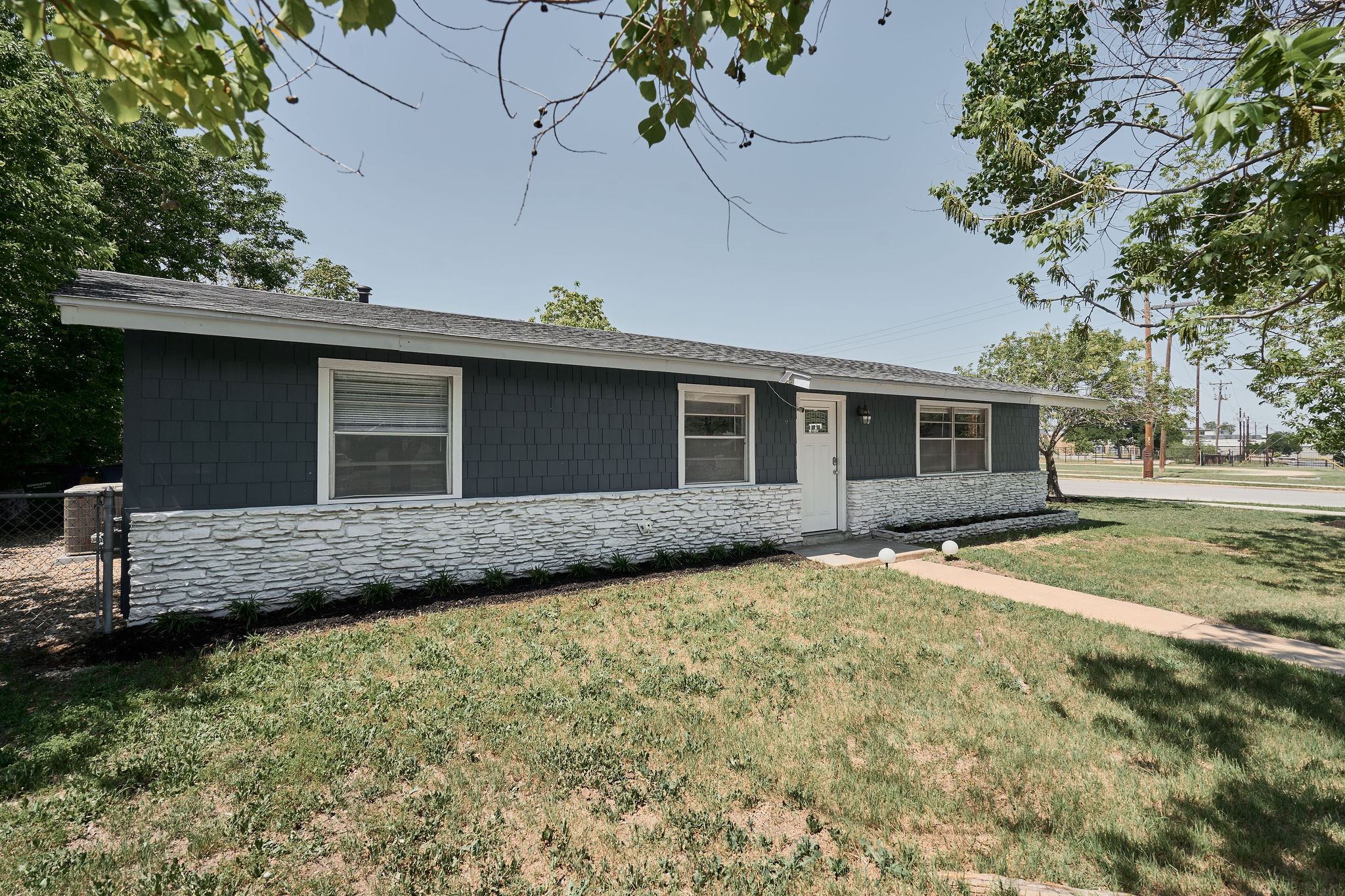 7706 Delafield Lane Austin, TX 78752 - Photo 9 of 28 Ranch-style house with stone siding, a front lawn, and roof with shingles