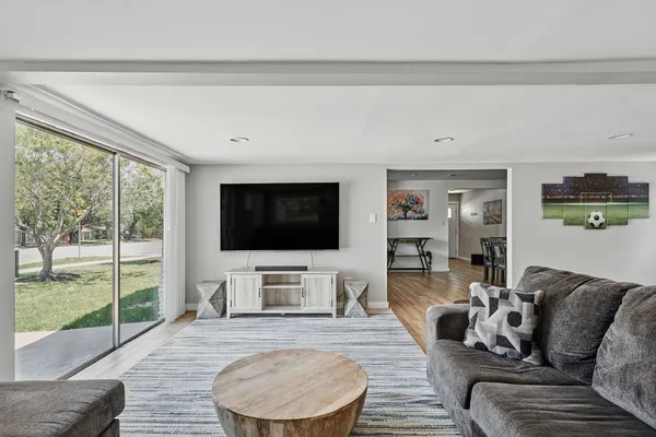 a living room with furniture a flat screen tv and a floor to ceiling window