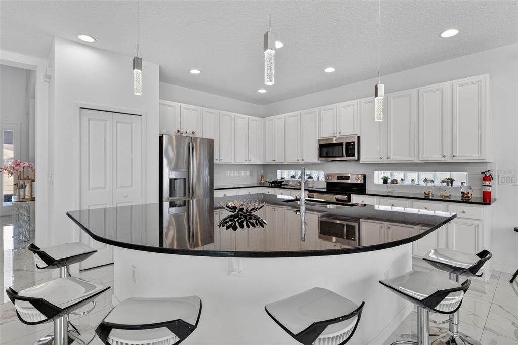 4577 Cabello Loop Kissimmee, FL 34746 - Photo 3 of 37 a kitchen with kitchen island granite countertop a stove a sink and a refrigerator