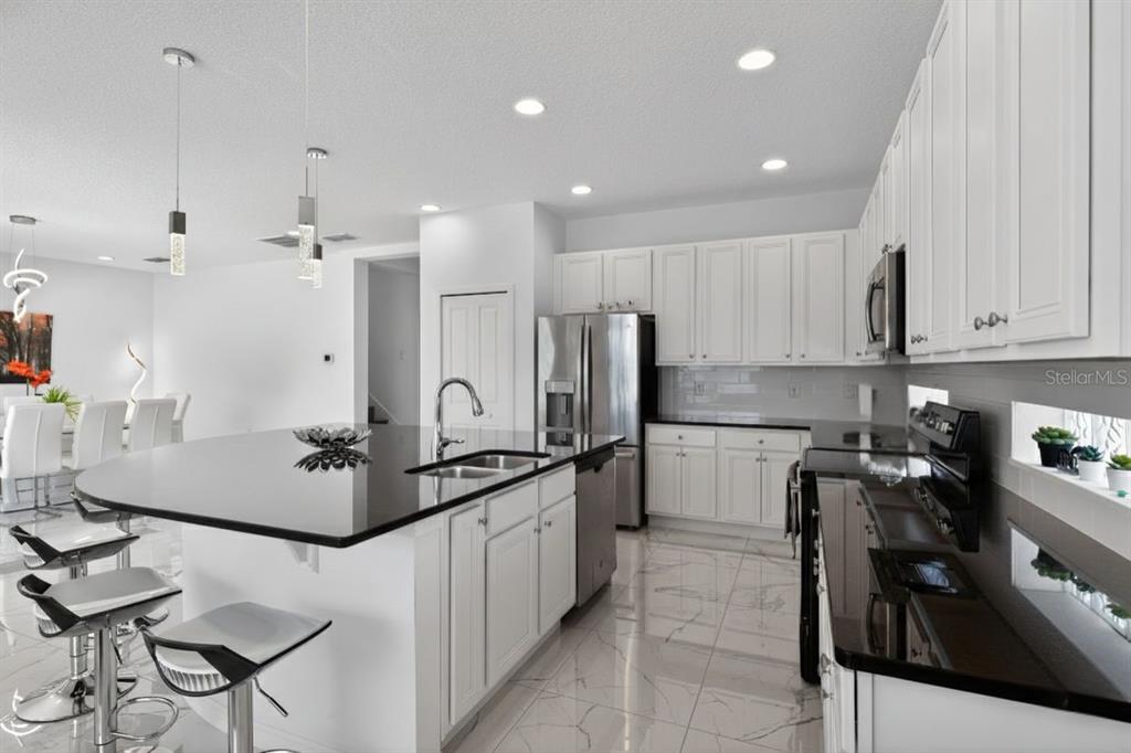 4577 Cabello Loop Kissimmee, FL 34746 - Photo 6 of 37 a kitchen with stainless steel appliances granite countertop a sink a stove a refrigerator and cabinets