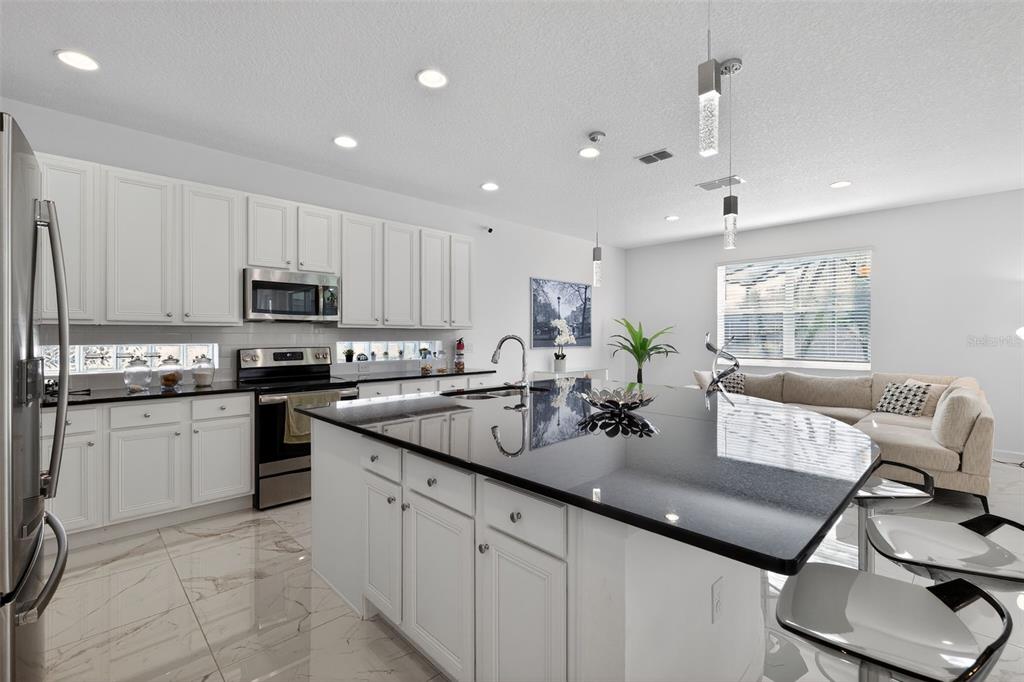 4577 Cabello Loop Kissimmee, FL 34746 - Photo 7 of 37 a kitchen with kitchen island granite countertop a sink counter top space appliances and cabinets