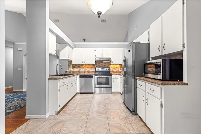 a kitchen with stainless steel appliances kitchen island granite countertop a stove a sink and a refrigerator