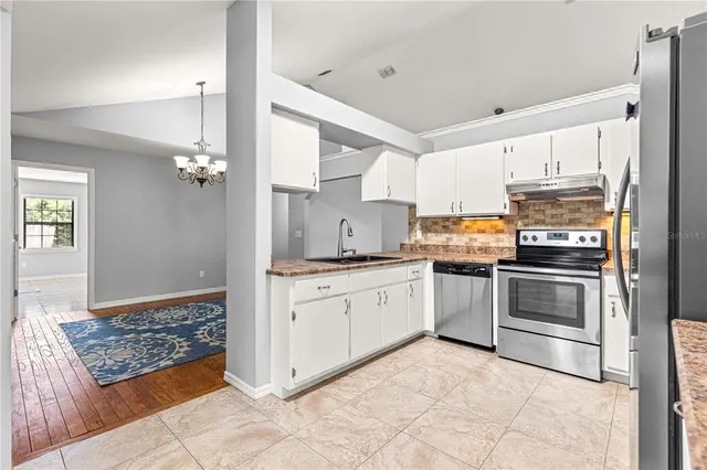 a kitchen with granite countertop a sink cabinets and stainless steel appliances