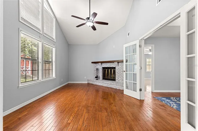 a view of an empty room and kitchen with ceiling fan