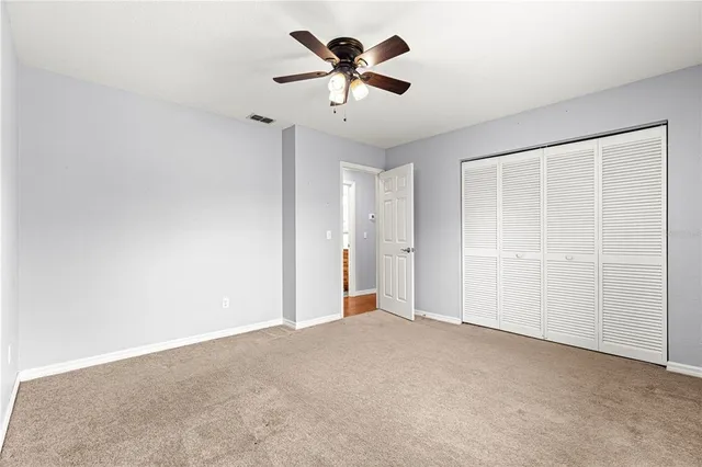 an empty room with chandelier fan and windows