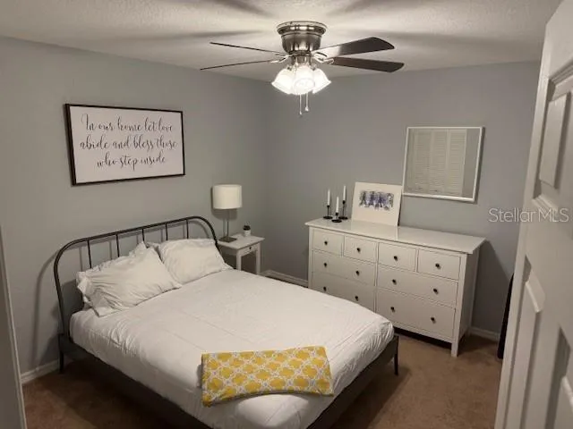 an empty room with chandelier fan and windows
