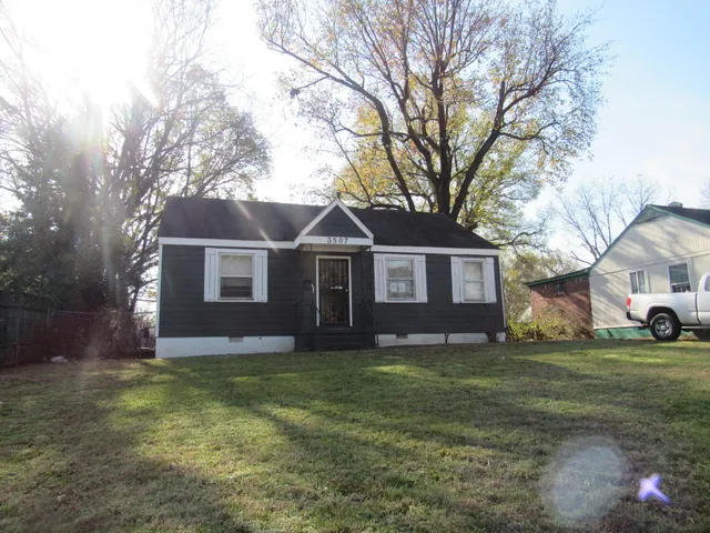 a view of a yard in front of a house with large tree