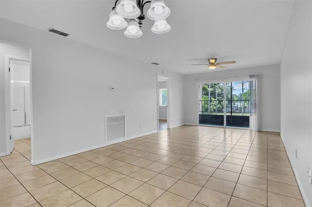 a view of an empty room and kitchen view with wooden floor