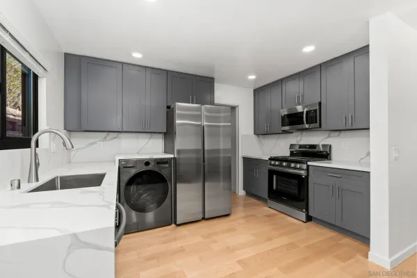 a kitchen with a refrigerator a stove top oven a sink dishwasher a dining table and chairs with wooden floor