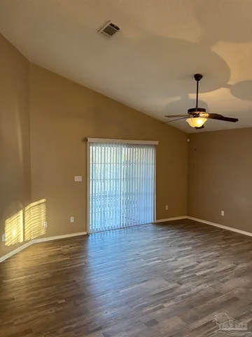 an empty room with wooden floor chandelier fan and windows