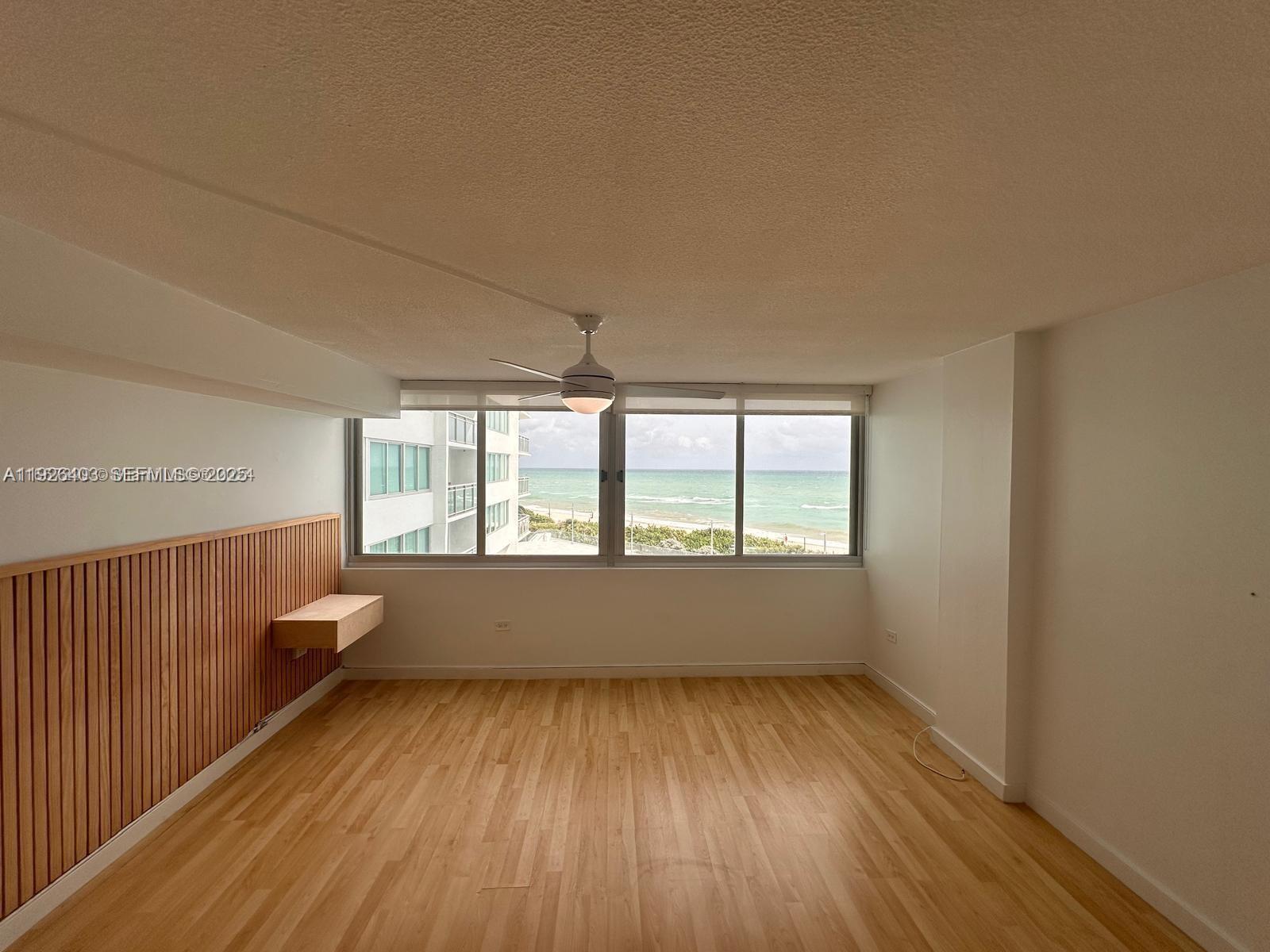7135 Collins Avenue, Unit 512 Miami Beach, FL 33141 - Photo 7 of 10 an empty room with wooden floor and windows