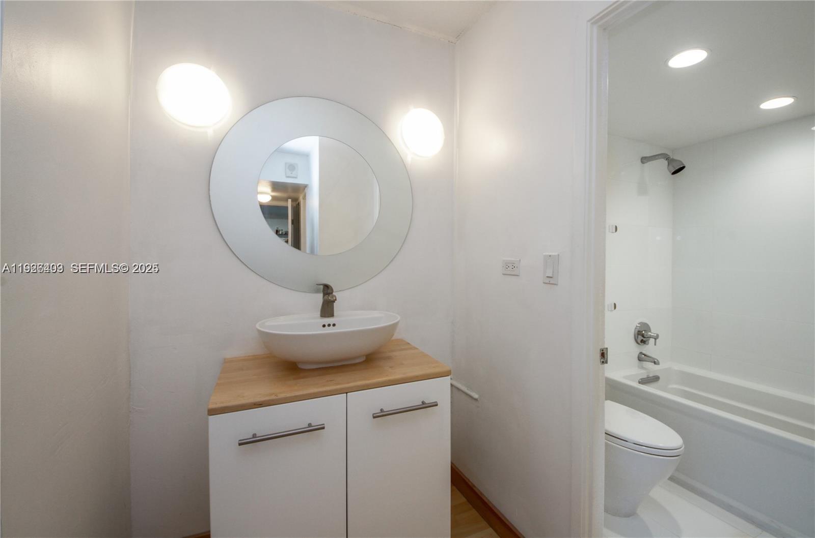 7135 Collins Avenue, Unit 512 Miami Beach, FL 33141 - Photo 9 of 10 a bathroom with a toilet a sink and mirror