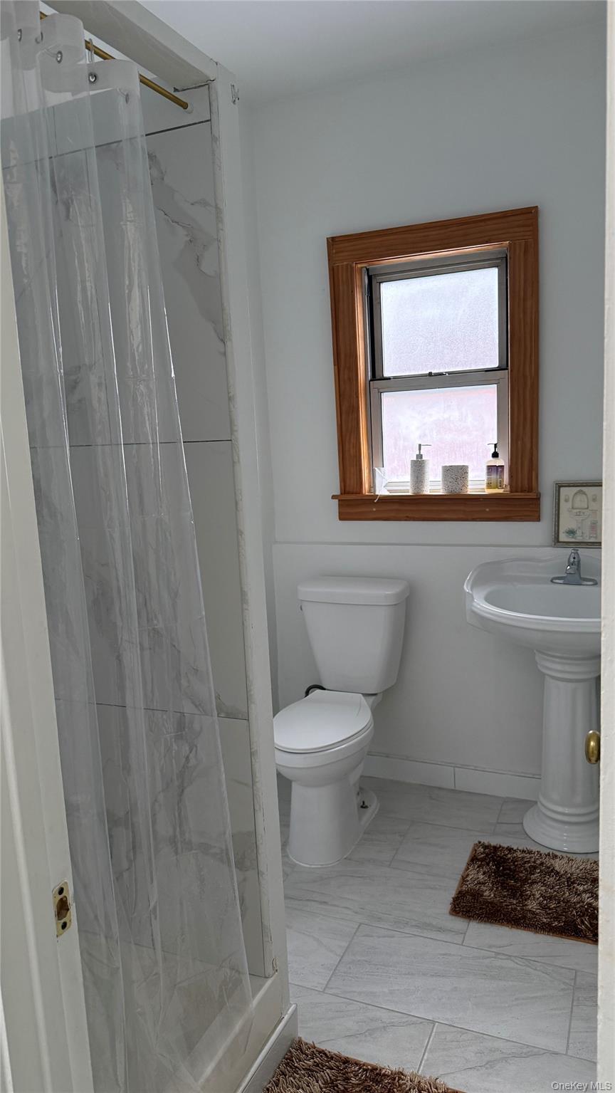 88-10 78th Street Queens, NY 11421 - Photo 12 of 19 a bathroom with a toilet a sink and a window